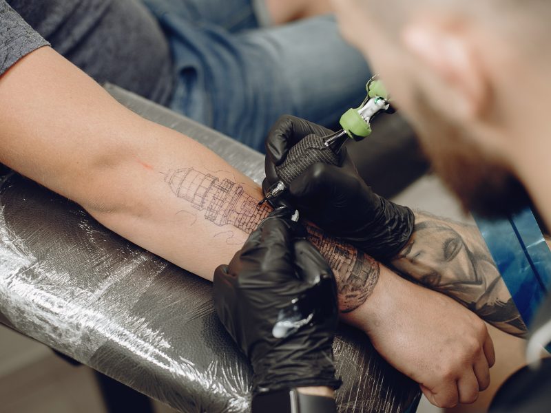 Persona haciendo el tatuaje de una torre en un brazo