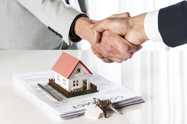 Dos personas dándose la mano tras firmar contrato inmobiliario