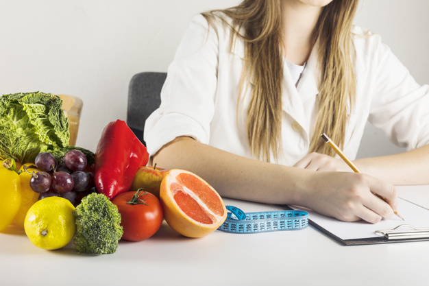 Mujer estudiando Curso de Nutrición y Dietética con frutas y verduras al lado