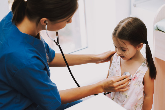 Médico de pediatría auscultando a una niña