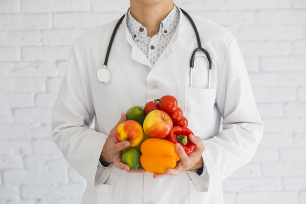 Nutricionista sosteniendo frutas y verduras entre sus manos